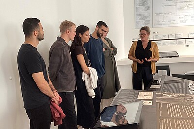 The descendants of the Oppenheim couple are standing in the historical site Stadthaus. They are listening to a member of the foundation's staff.